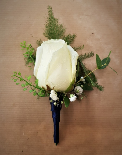 White Rose Buttonhole - Designer White rose buttonhole with foliage and gypsophila wrapped with satin ribbon Buttercups & Daisies Florist Birmingham creates this White Rose Buttonhole as part of a coordinated floral look for ceremonies and receptions. The florists can discuss how colours, shapes and flower choices may work alongside other ceremony or reception arrangements. Flower varieties and foliage depend on seasonal supply; suitable substitutions may therefore be used while preserving the overall style, value ...