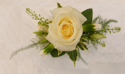 White Rose Wrist Corsage - White avalanche rose wrist corsage on a pearl wrist band with complimenting foliage Designed with wedding styling in mind, this White Rose Wrist Corsage is arranged locally in Birmingham with careful attention to presentation. The team considers venue style, photography, seasonal colour and surrounding décor when discussing a coordinated design. Because fresh flowers naturally change through the year, particular varieties may be substituted with comparable choices that retain the intended p...