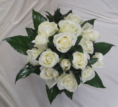 Rose Bride Posy - White avalanche roses with pearl pins in centres mixed with ruscus leaves and surrounded with fatsia leaves and finished with white satin ribbon This Rose Bride Posy is prepared by Buttercups & Daisies Florist Birmingham for weddings, civil ceremonies and elegant celebrations. Proportion, movement, complementary shades and finishing details are balanced for an elegant appearance throughout the celebration. Seasonal availability can affect individual stems, but the florist will protect the de...