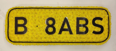 Rear Number plate funeral tribute - This Funeral tribute is created using yellow double chrysanthemums and can be personalised Designed and made by Buttercups & Daisies Florist Birmingham, this Rear Number plate funeral tribute offers families a personal way to express remembrance through flowers. The design is assembled patiently, with suitable blooms and foliage positioned to maintain a clear form and balanced character. Flower varieties and foliage depend on seasonal supply; suitable substitutions may therefore be used whil...