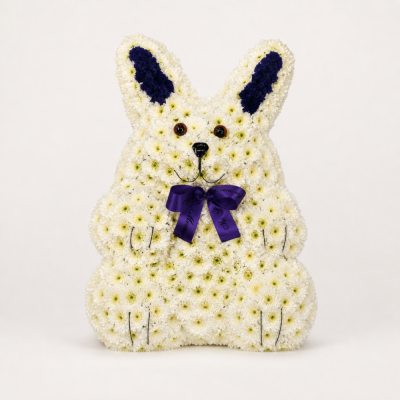 Floral Bunny Tribute - This gentle floral bunny tribute is created in creamy white flowers with deep purple inner ears, carefully formed facial features and a matching purple memorial bow.